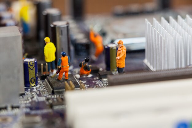 trabajadores miniatura que trabajan en el chip de la placa base