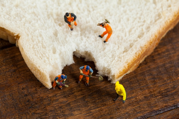 trabajadores miniatura que trabajan en rodajas de pan