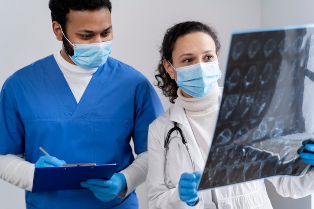 Trabajadores de la salud de tiro medio mirando una radiografía.