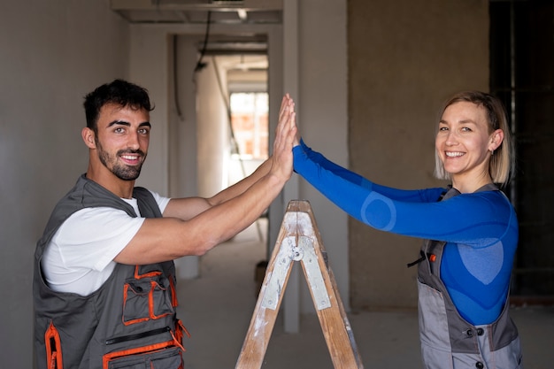 Los trabajadores sonrientes de tiro medio chocan los cinco