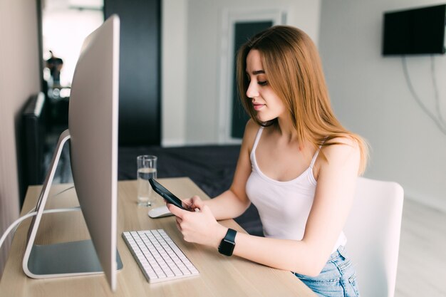 Trabajar desde el concepto de hogar con una mujer que trabaja en un teléfono inteligente y una computadora portátil