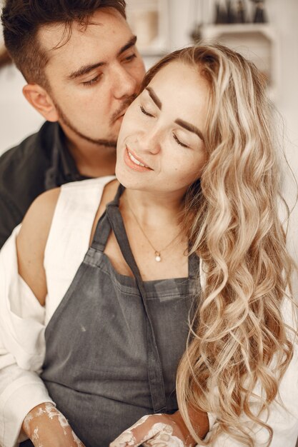 Trabajo creativo mutuo. Hermosa joven pareja en ropa casual y delantales. Personas creando un cuenco en un torno de alfarería en un taller de arcilla.