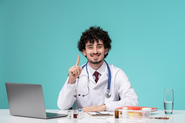 Trabajo médico en computadora remotamente serio lindo doctor inteligente en bata de laboratorio levantando el dedo feliz