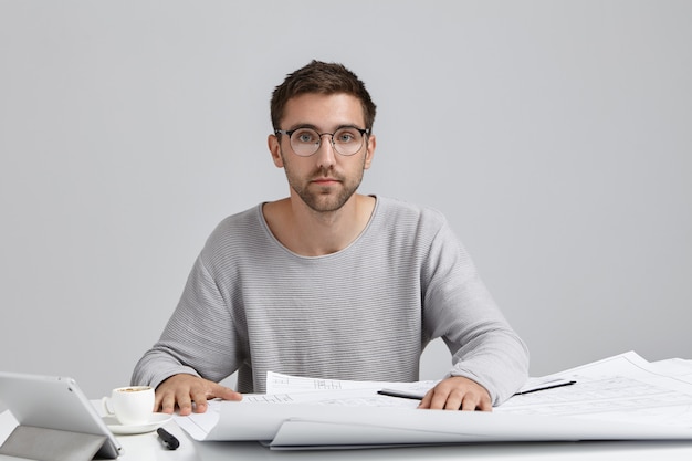 Foto gratuita trabajo, tecnologías modernas, creatividad y concepto de ocupación. imagen de guapo joven ingeniero con barba recortada