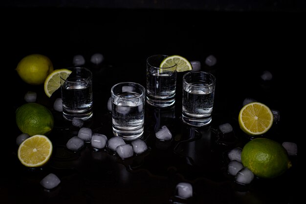 Tragos de alcohol con cal y cubitos de hielo en negro