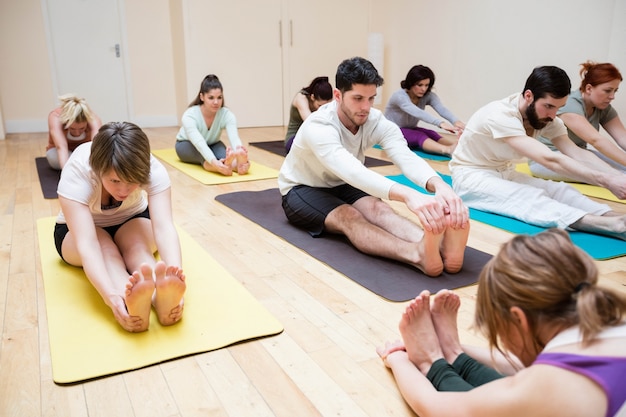 Foto gratuita trainer grupo de personas ayudando con el ejercicio pashimottanasana