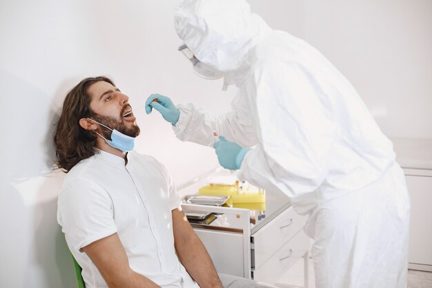 Traje protector médico y mascarilla quirúrgica. Hisopo de algodón de la garganta y la nariz del paciente. Prueba de coronavirus, prueba de infección por covid-19 en una pandemia.