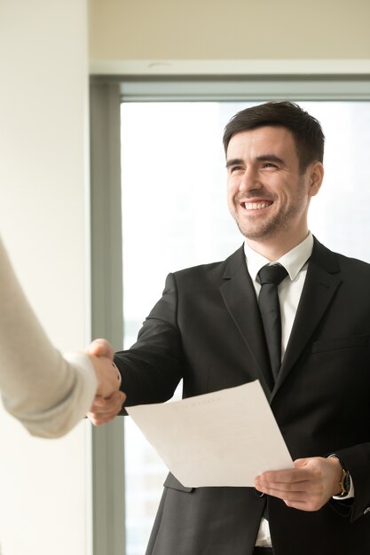 Traje que lleva sonriente feliz del hombre de negocios que sacude la mano femenina