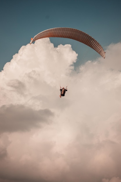 Foto gratuita tranquilo paisaje de parapente en el cielo nublado - tiro vertical