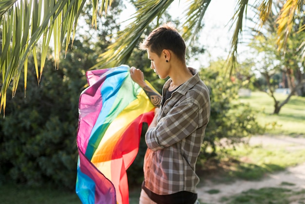 Transgénero manteniendo la bandera LGBT en el parque