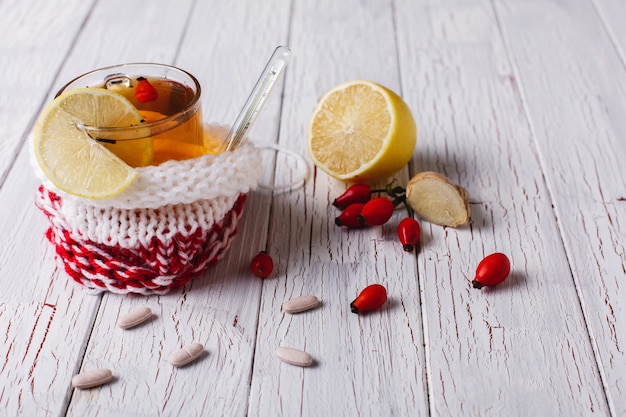 Tratamiento del resfriado. La taza con té caliente con el limón y las bayas se coloca en una tabla