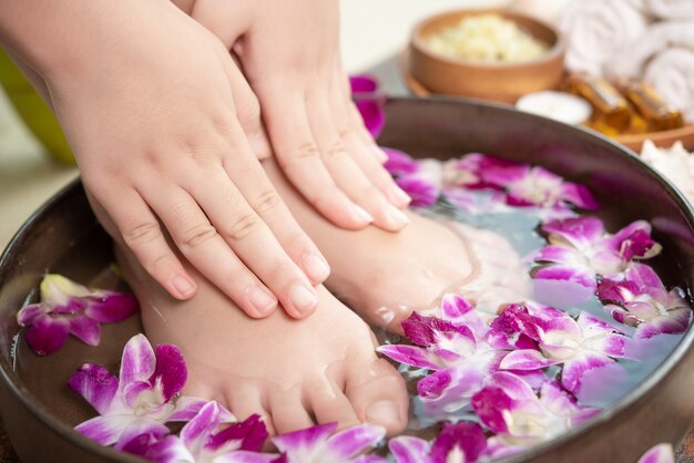 Tratamiento de spa y producto para pies femeninos y spa de manos. flores de orquídeas en cuenco de cerámica.