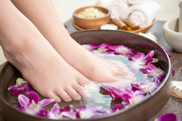 Tratamiento de spa y producto para pies femeninos y spa de manos. flores de orquídeas en cuenco de cerámica.