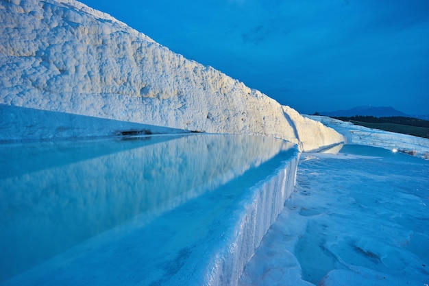 Travertinos de pamukkale en primer plano cielo del atardecer y casas iluminadas