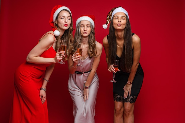 Tres alegres amigas con hermosos vestidos celebran el año nuevo y se regocijan juntas