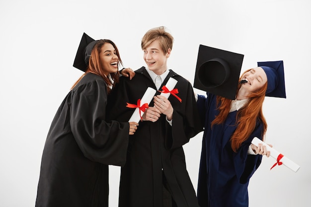 Tres alegres compañeros graduados celebrando sonriente regocijo. Futuros abogados o médicos, concepto de educación.