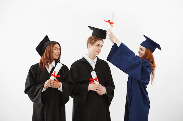 Tres alegres graduados sonrientes hablando engañando con diplomas.