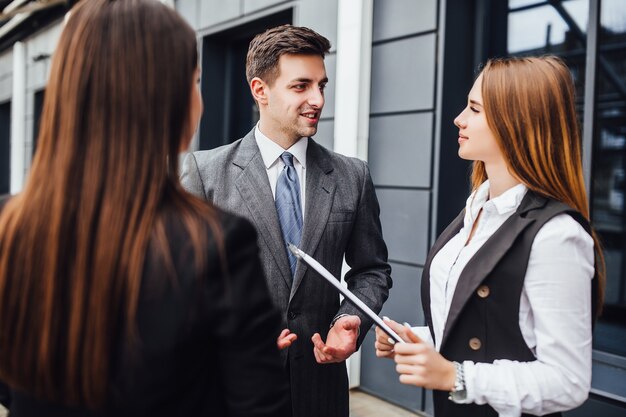 Tres alegres jóvenes empresarios hablando entre sí mientras camina al aire libre