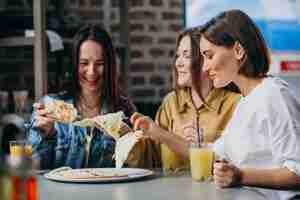 Foto gratuita tres amigas comiendo pizza en un bar