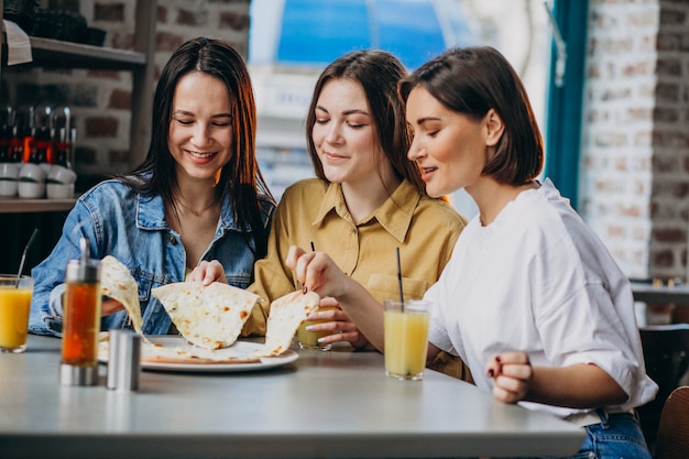 Tres amigas comiendo pizza en un bar