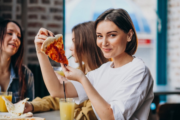 Tres amigas comiendo pizza en un bar