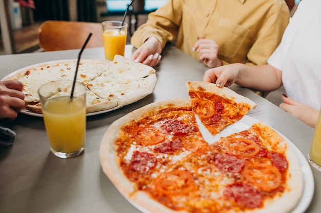 Foto gratuita tres amigas comiendo pizza en un bar