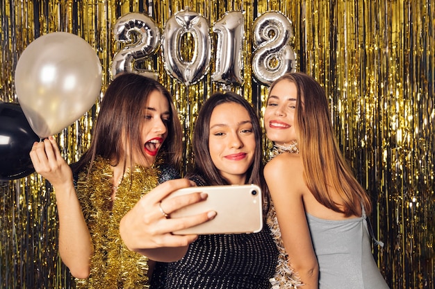 Tres amigas jóvenes haciendo un selfie en celebración de año nuevo
