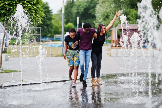 Tres amigos afroamericanos caminando sobre fuentes divirtiéndose juntos