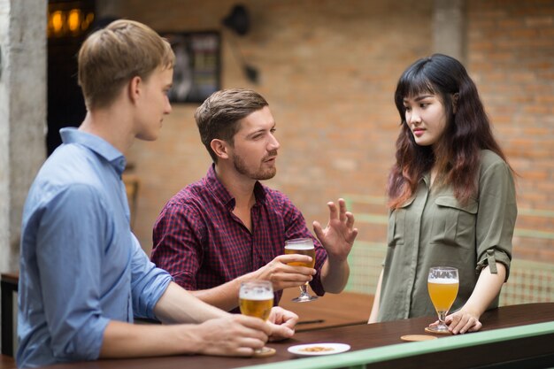 Tres amigos charlando y bebiendo cerveza en Pub