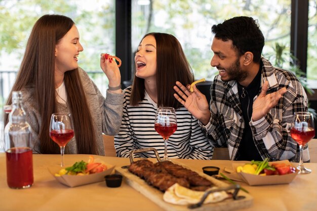 Tres amigos comiendo y bebiendo en una tertulia.