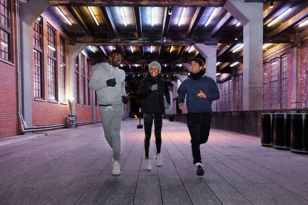 Foto gratuita tres amigos corriendo de noche en la ciudad.