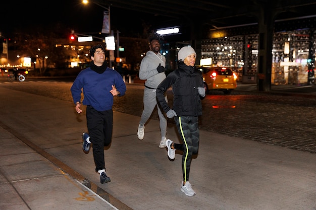 Foto gratuita tres amigos corriendo de noche en la ciudad.