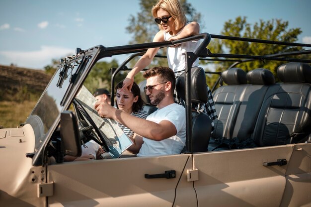 Tres amigos felices revisando el mapa mientras viaja en coche