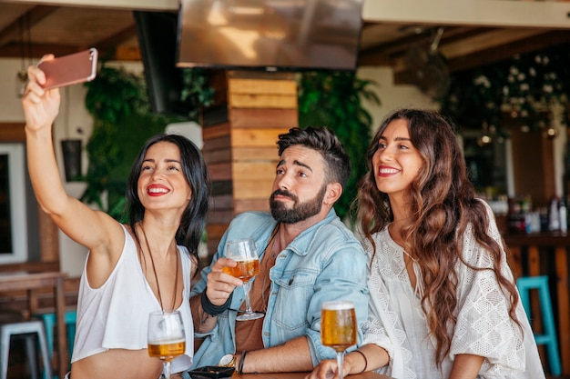 Foto gratuita tres amigos haciendo un selfie en bar