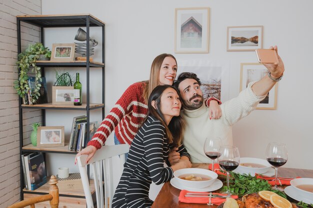 Tres amigos haciendo selfie en cena de navidad