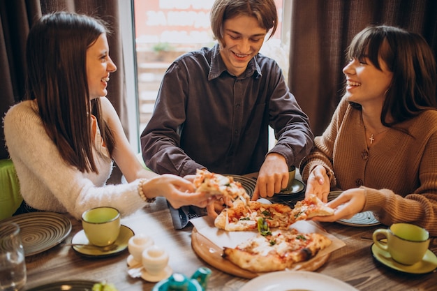 Tres amigos juntos comiendo pizza en un café