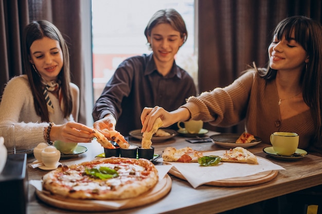 Tres amigos juntos comiendo pizza en un café