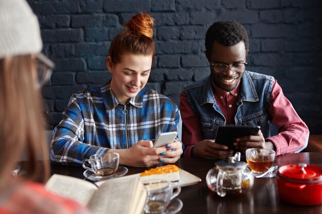 Tres amigos que pasan un buen rato juntos, disfrutan de una conversación animada en el café, comen postre y beben té. Gente, estilo de vida