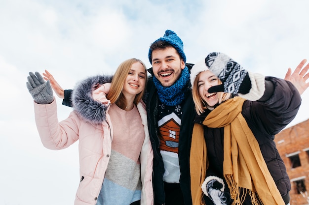 Foto gratuita tres amigos en ropa de invierno agitando con las manos afuera