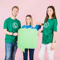 Foto gratuita tres amigos sonrientes sosteniendo el bocadillo de diálogo verde vacío