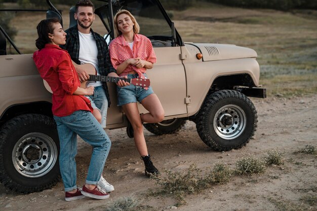 Tres amigos sonrientes tocando la guitarra mientras viaja en coche