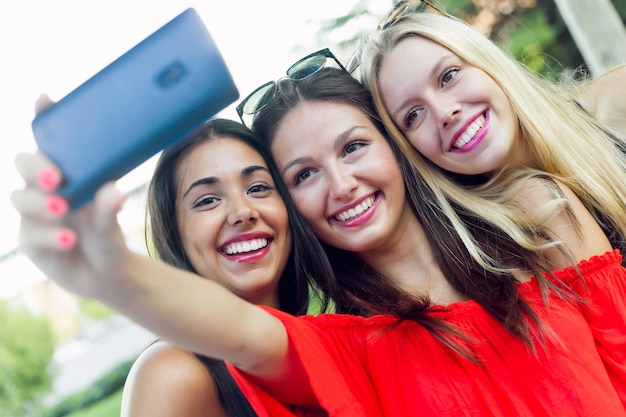 Tres amigos tomando fotos con un teléfono inteligente en la calle.