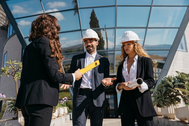 Foto gratuita tres arquitectos hablando enfrente de edificio de cristal