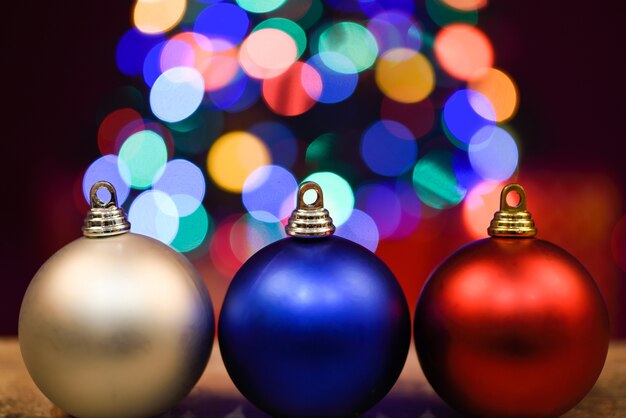 Tres bolas de navidad en una tabla de madera oscura con bokeh en el fondo