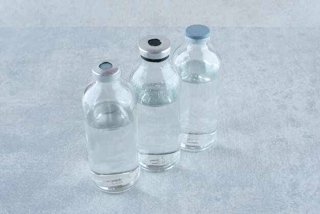 Tres botellas de etanol médico sobre superficie gris