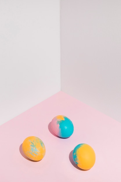 Foto gratuita tres brillantes huevos de pascua esparcidos sobre la mesa