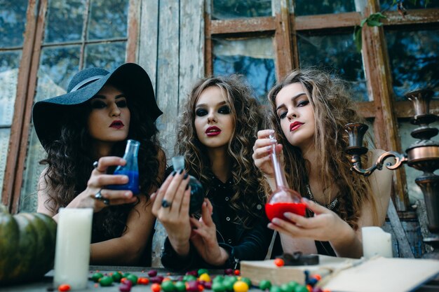 Tres brujas están sentadas a la mesa y prepararon la poción en vísperas de Halloween