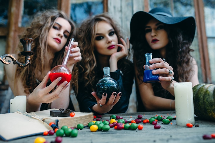 Foto gratuito tres brujas están sentadas a la mesa y prepararon la poción en vísperas de halloween
