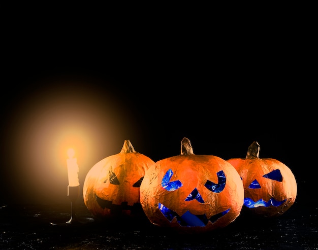 Foto gratuita tres calabaza de halloween tallada con candelabro brillante