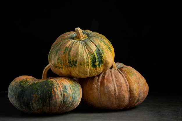 Tres calabazas colocadas en un piso oscuro.